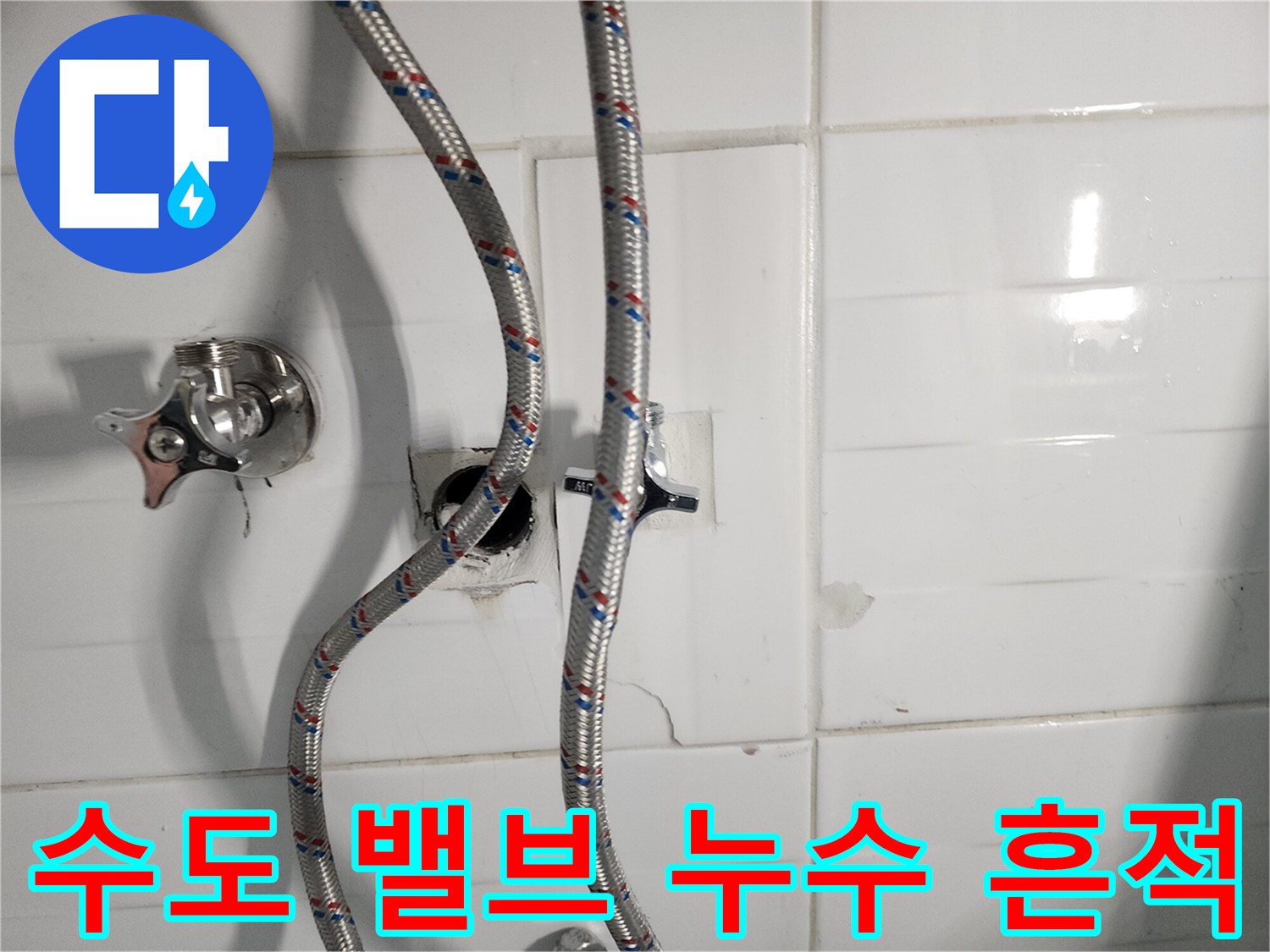 화장실 타일 벽면에 설치된 수도 밸브와 연결 호스 모습입니다.