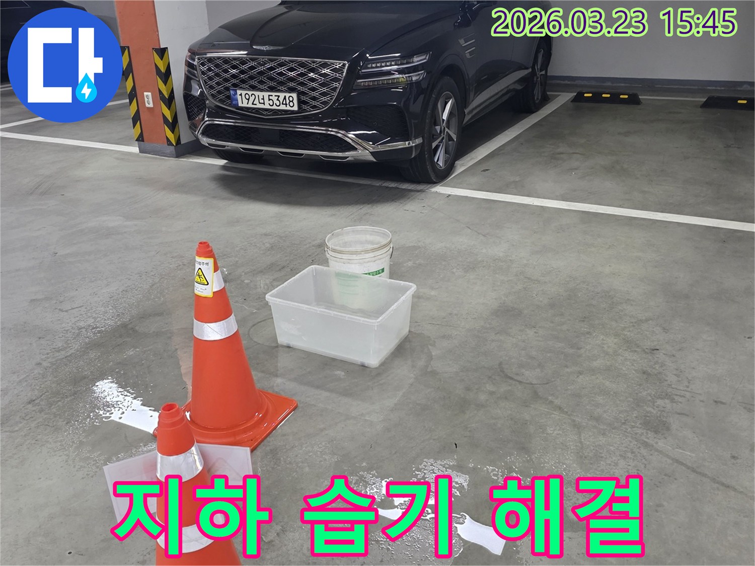 주차장 바닥에 물이 새어-안전 콘과 물받이로 임시 조치된-누수 현장을 보여줍니다.