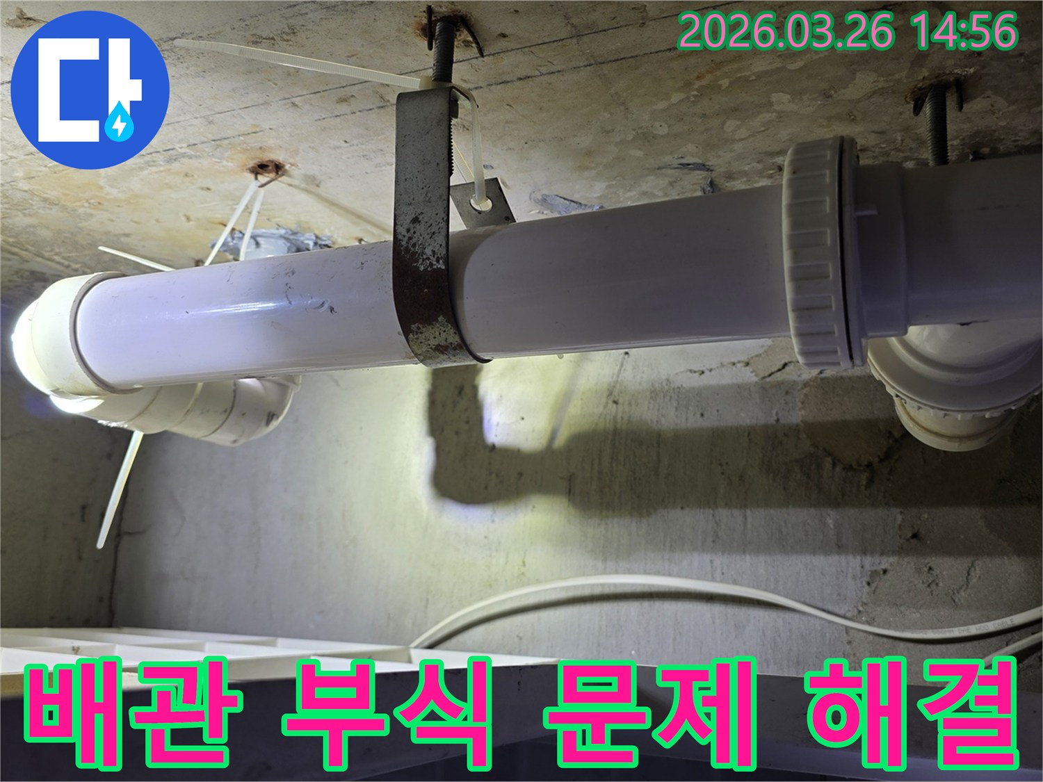 콘크리트 천장에 고정된-하얀색 배관과-녹슨 금속 지지대의 모습으로-배관 부식 문제 해결 현장을 보여줍니다