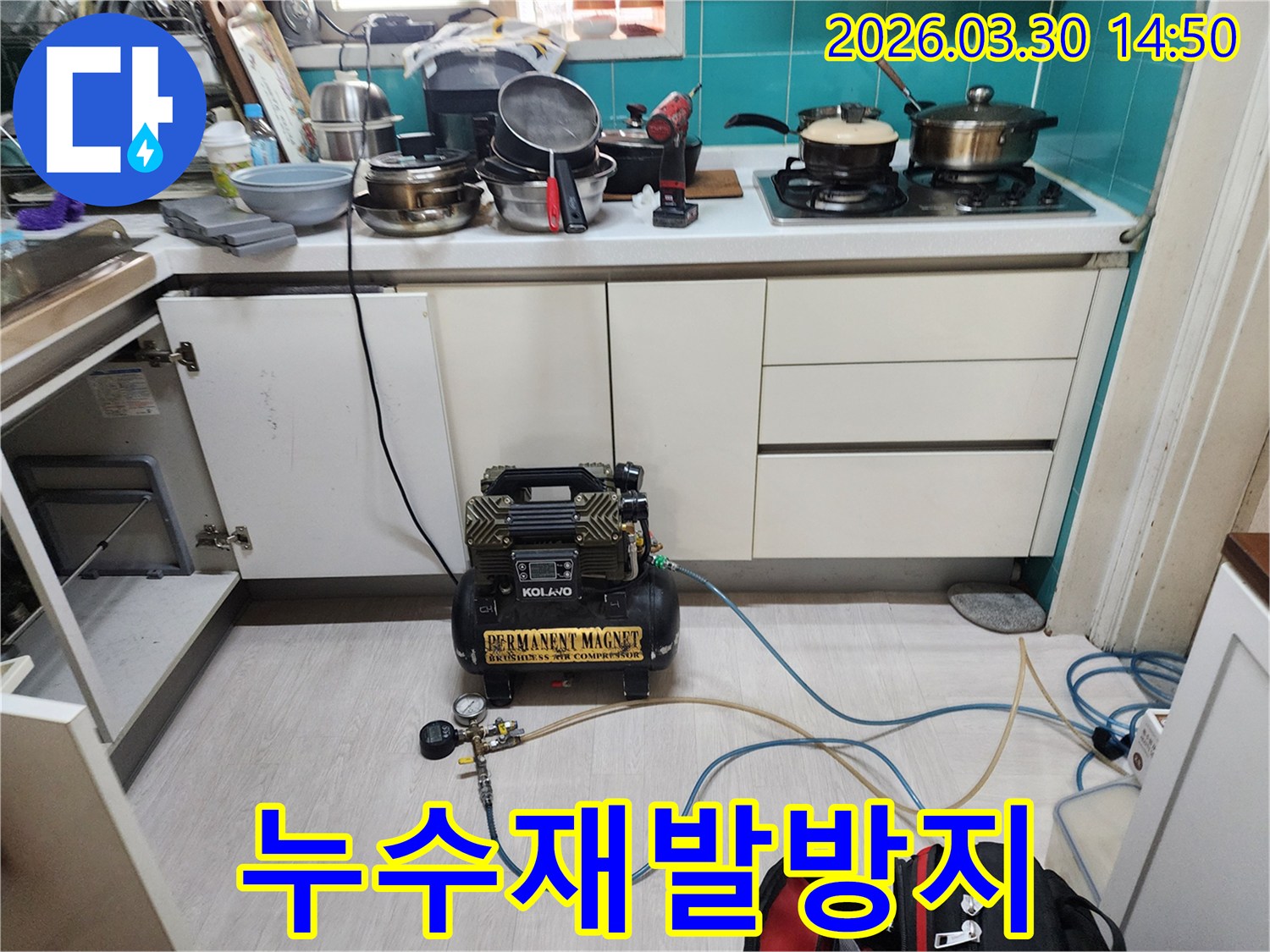 주방 하부장 안쪽에서-누수 재발 방지를 위한 공사 전-최종 누수 지점 확인을 위해-공압 장비가 연결되어 있습니다.