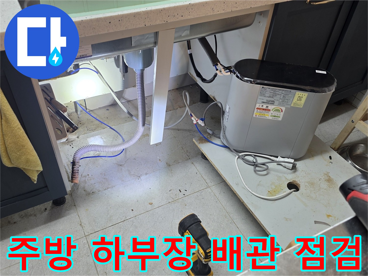 주방 싱크대 밑 배수 호스와 주변 장비 모습입니다.