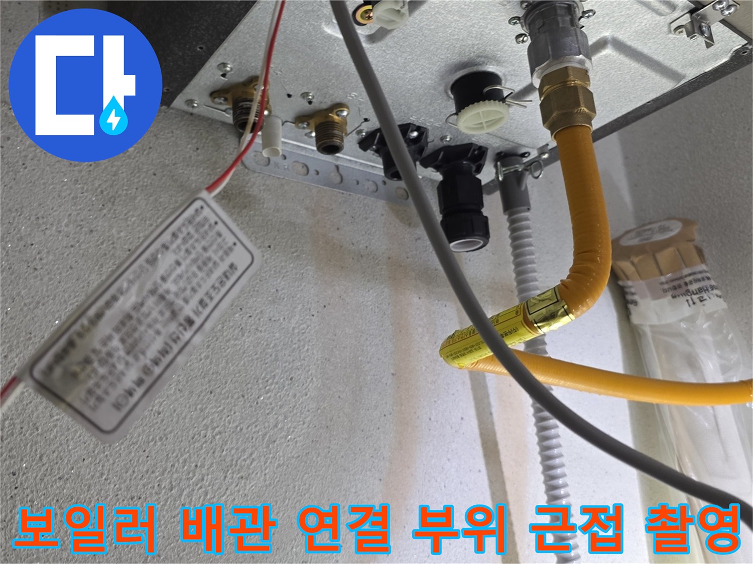 보일러 하단부-노란색 온수 배관과 금속 커플링의 모습입니다.
