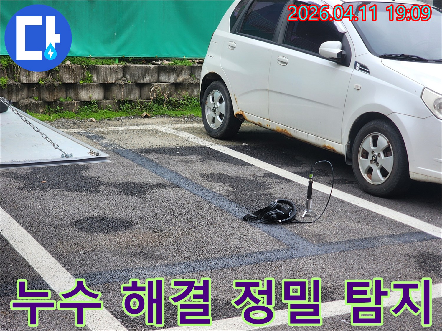주차장 바닥의 물기 흔적을 따라-누수 지점을 찾기 위해-전문 탐지 장비가 사용되어-정밀 탐지가 진행되고 있습니다.