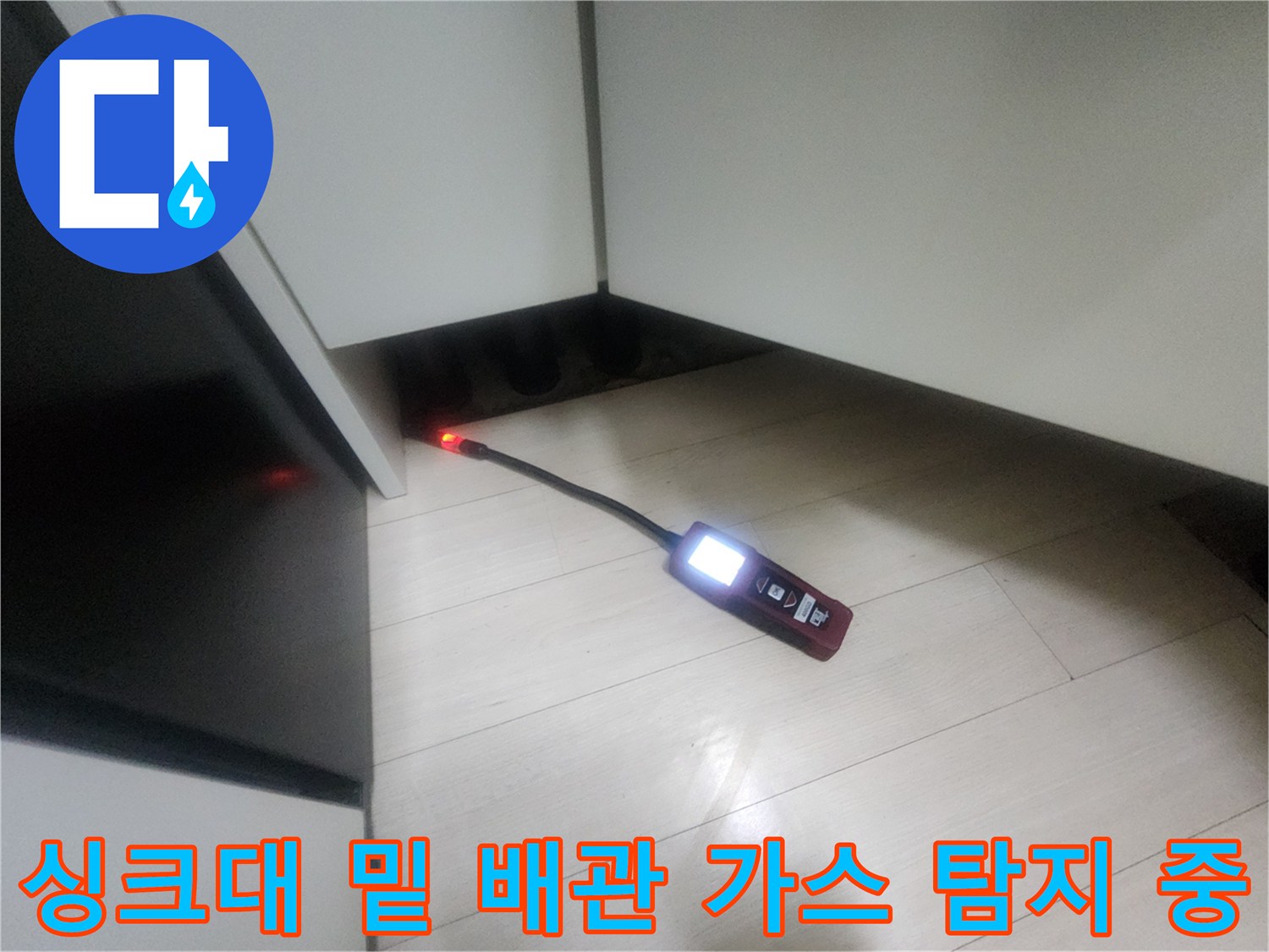 배관의 미세한 결함을 찾기 위해 가스 탐지기를 싱크대 하단부에 투입하여 검사하는 모습입니다.