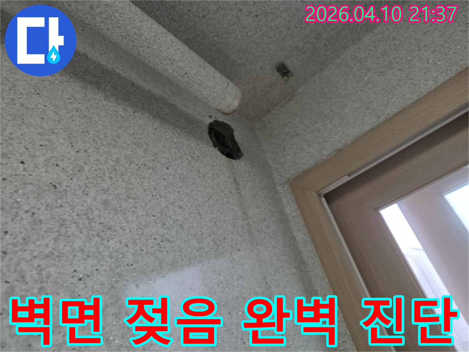 벽면의 구멍과-그 아래로 흐른 물자국을 통해-누수 지점을 시각적으로 보여주는 사진입니다