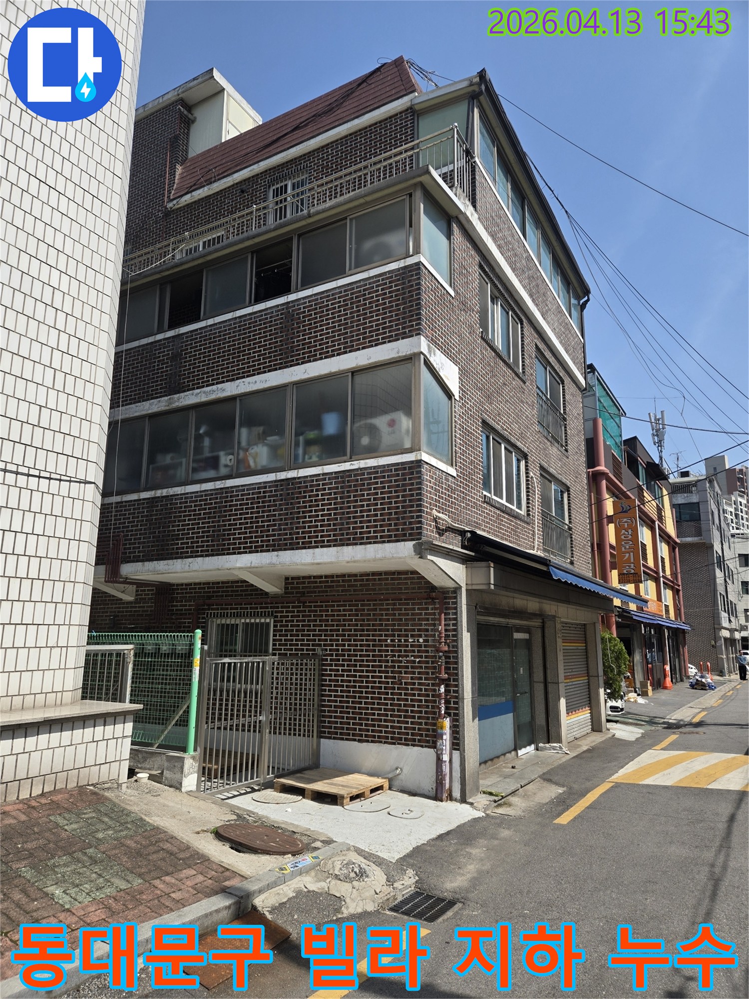 동대문구의-빌라-건물-외관을-보여주는-이-사진은-지하-주차장-침수-문제로-인한-누수-원인을-찾기-위해-전문-엔지니어가-현장을-점검하는-모습입니다.