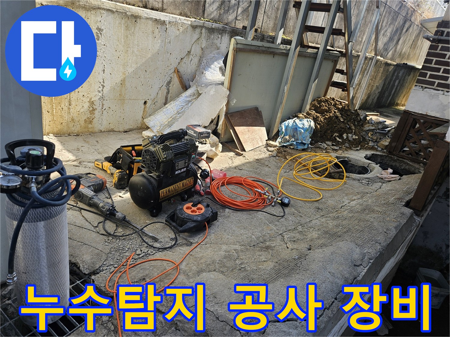 누수 공사 현장에서-에어 콤프레셔와-함마드릴-호스-전선릴 등-다양한 작업 도구들이-콘크리트 바닥 위에-준비되어 있는 모습