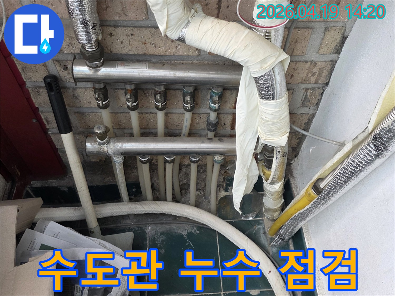 오래된 아파트의 수도관과 분배기 연결 부위에서 누수 여부를 면밀히 점검하는 모습
