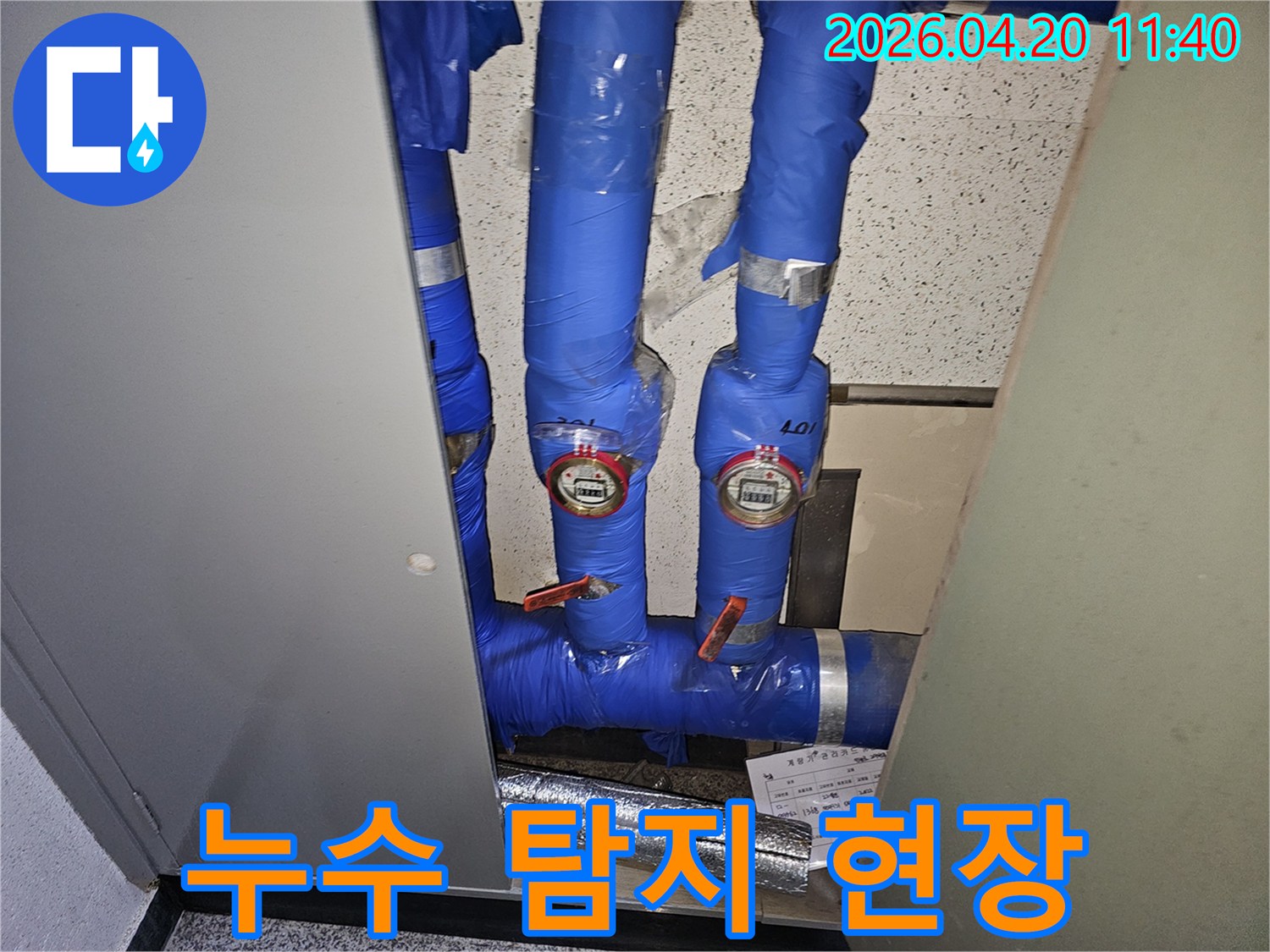 파란색으로-단열된-파이프와-두 개의-수도계량기가-설치된-공간의-누수-확인-사진입니다.