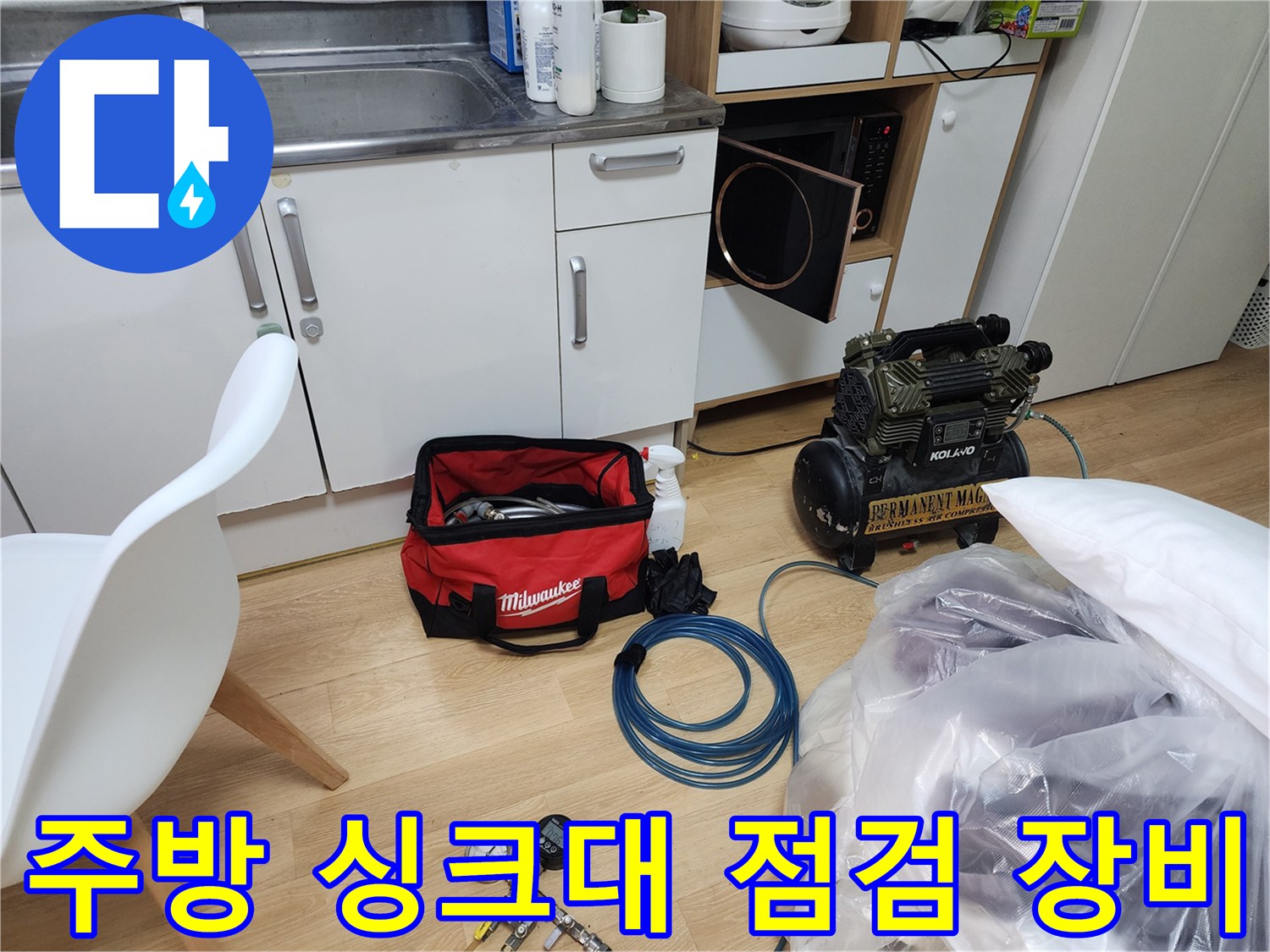 주방 싱커대 하부장 근처에 놓인 누수 탐지용 정밀 장비와 공압 테스트 도구들입니다.