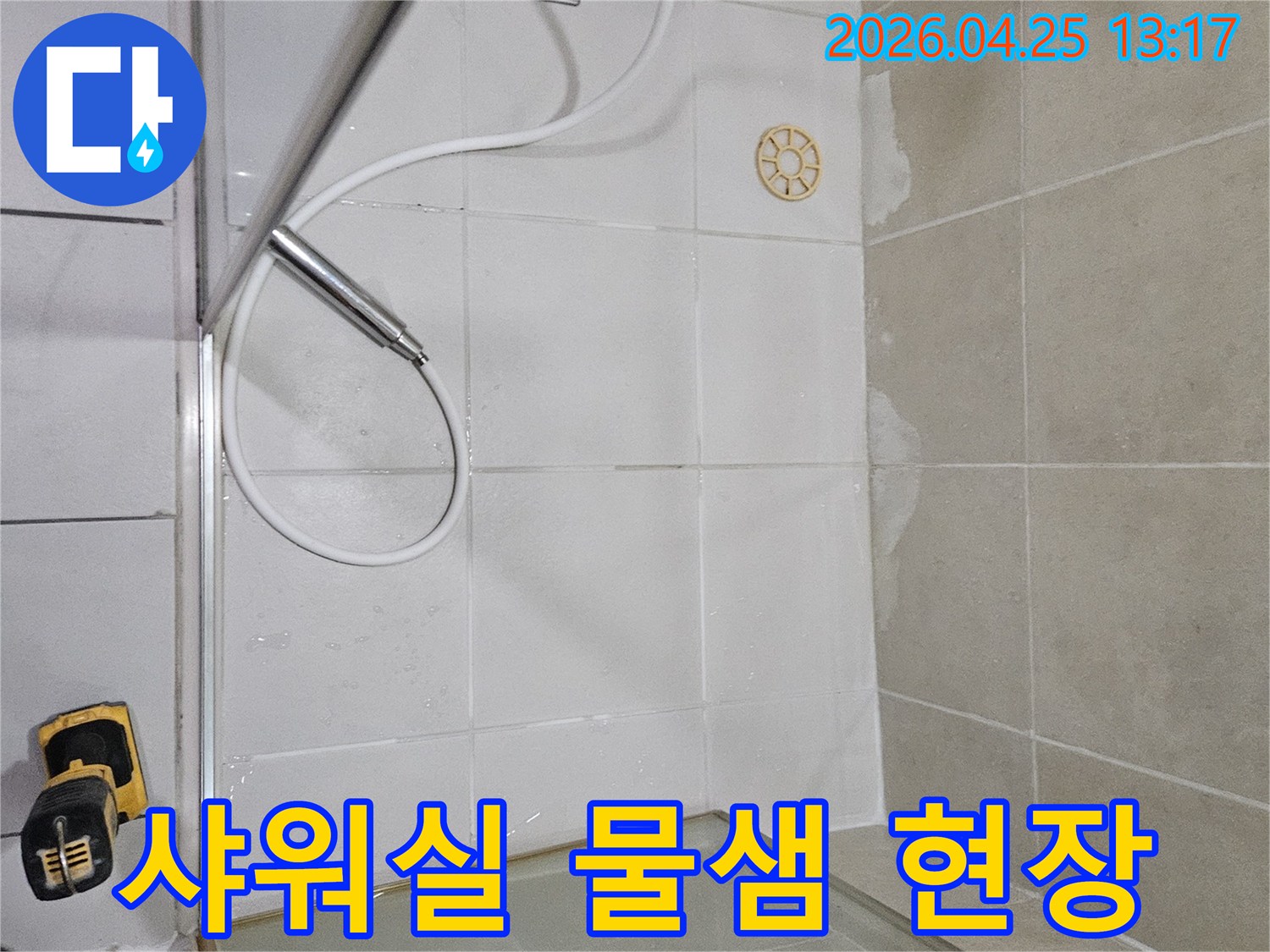 샤워실 바닥과 벽면 경계에서 발견된 물샘 흔적을-육안으로 면밀히 검사하는 현장 사진입니다.