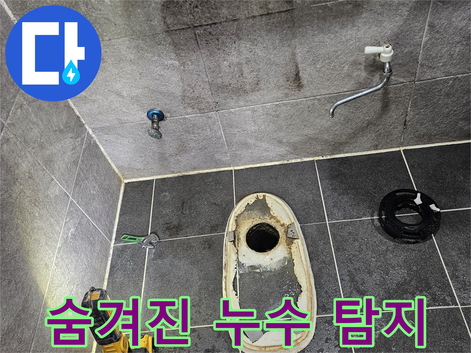 변기가 제거된 욕실 바닥의 물샘 흔적을-손전등으로 확인하며-보이지 않는 곳에 숨겨진 누수 지점을 찾아내기 위한 정밀 탐지를 시작하는 모습입니다.
