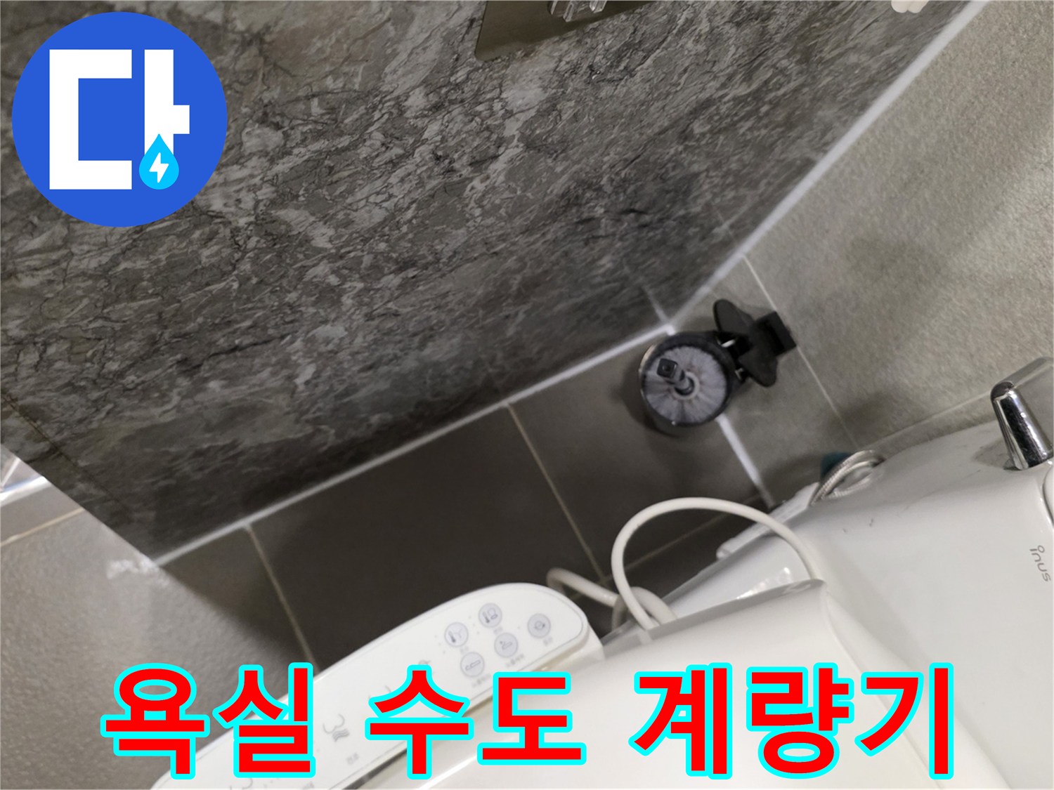 화장실 벽면 하단에 위치한 수도 계량기와 타일 마감
