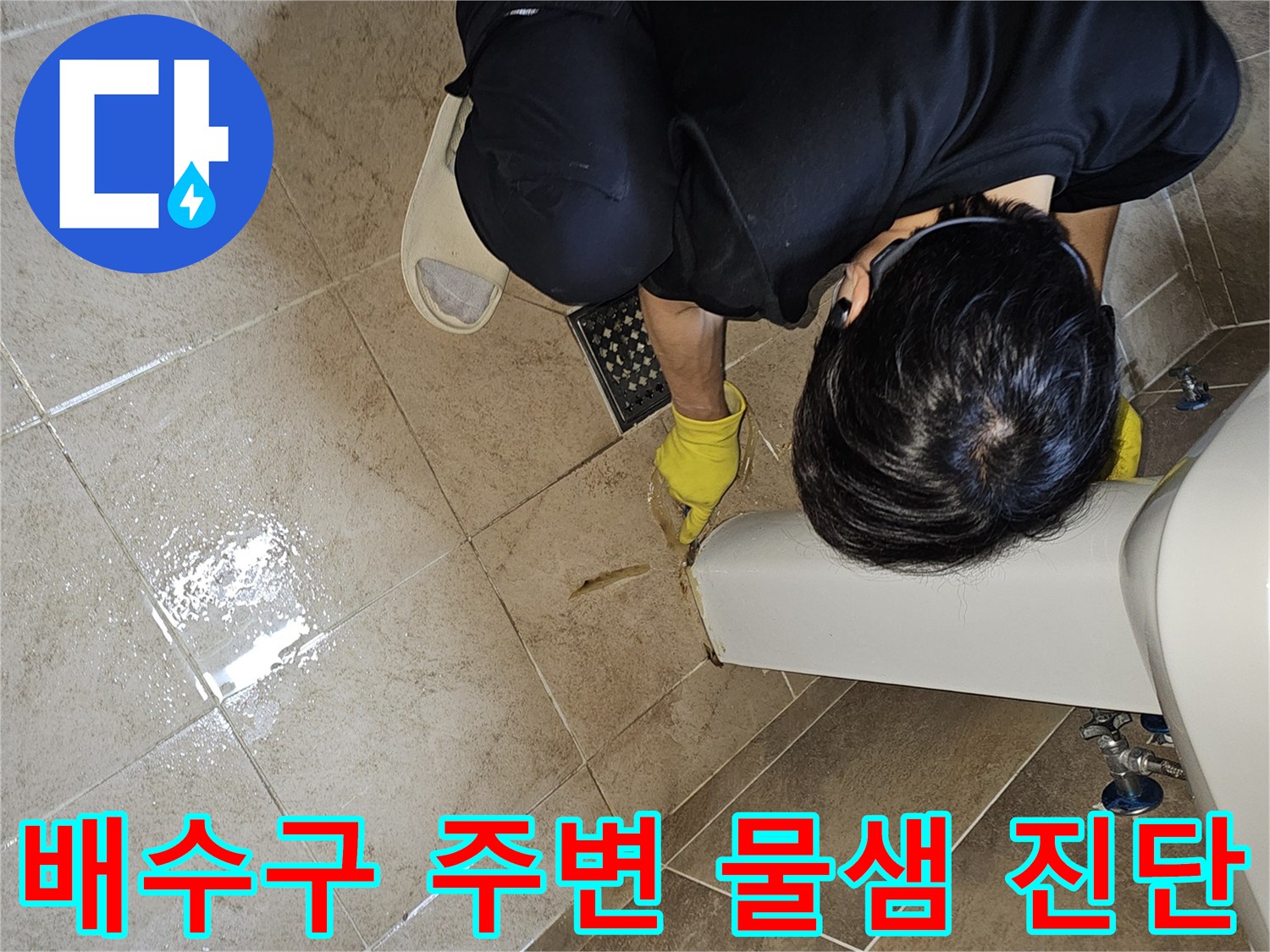누수 전문가가-노란 장갑을 끼고-욕실 바닥 배수구 주변의-젖은 타일과-틈새를 집중적으로 관찰하며-누수 지점을 파악하고 있습니다