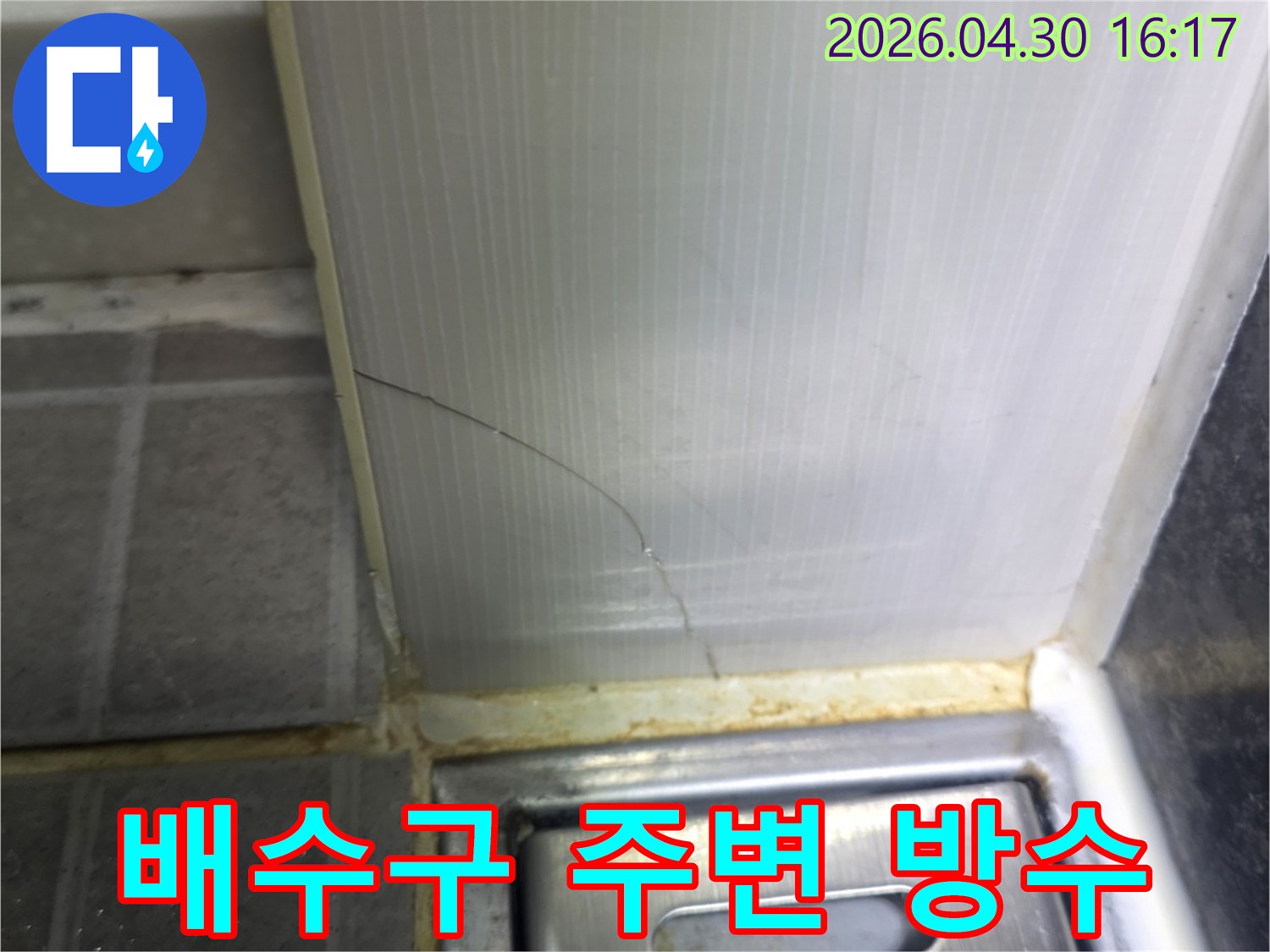 욕실 배수구 근처의-벽면과 바닥 연결부 실리콘에-발생한 균열과-오염된 흔적을 보여주는 상세 이미지입니다.