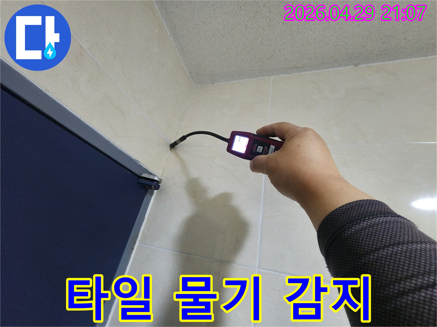 누수 전문 엔지니어가-타일 벽면의 미세한 틈새에서-고성능 탐지기로-숨겨진 물기를 정확히 감지하고 있습니다.
