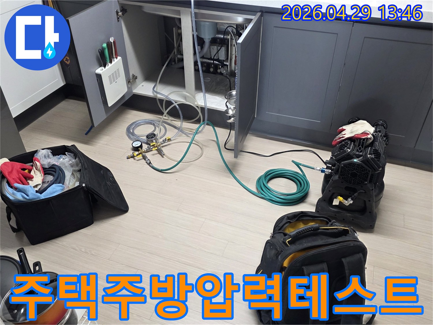 비산동 주택의 주방 싱크대 하부에서-누수 확인을 위한-배관 압력 테스트 장비와-호스를 연결하여-테스트를 준비하는 모습입니다