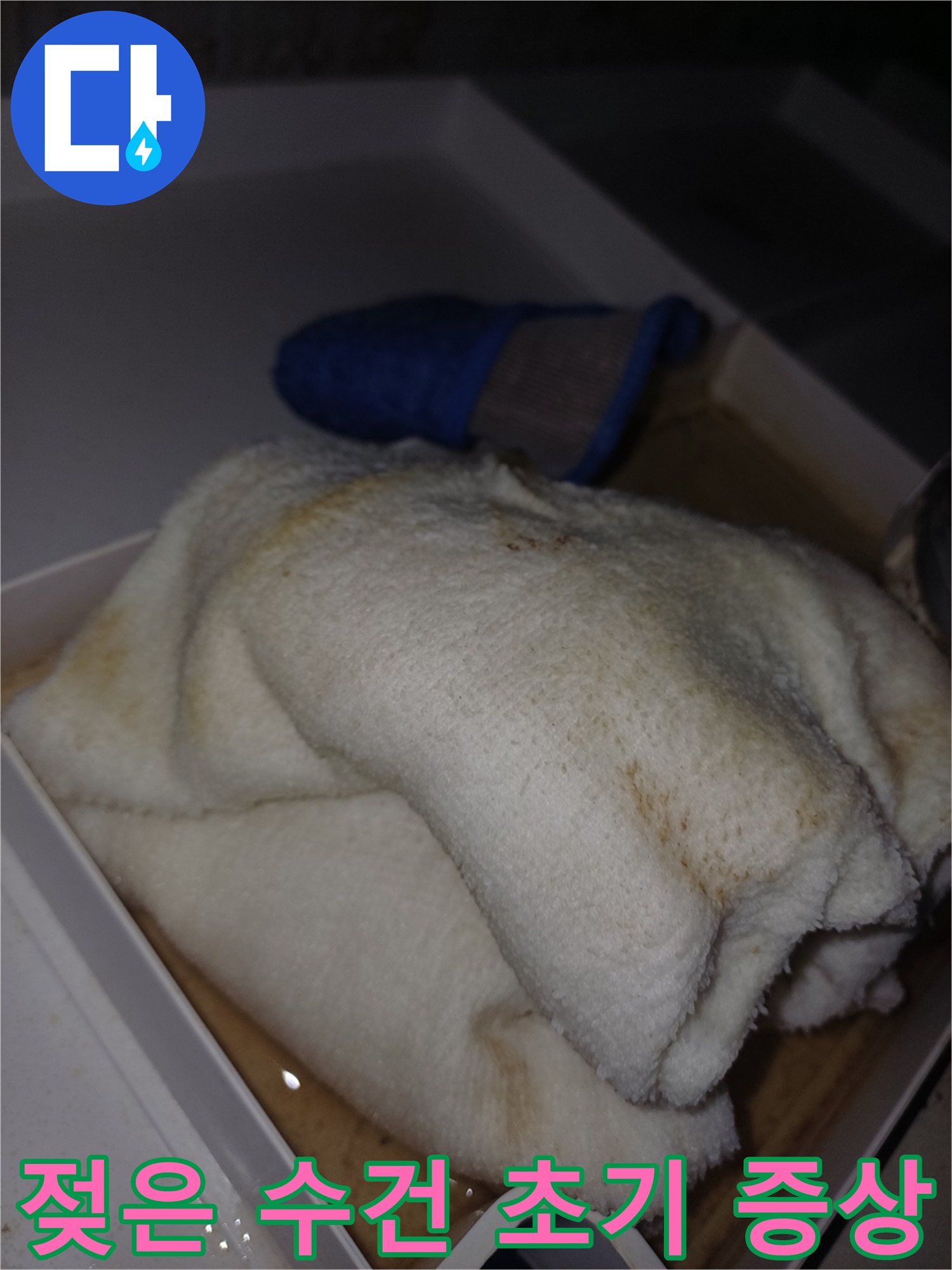 물에 젖어 얼룩이 생긴 수건이 상자 안에 놓여 있는-누수 피해가 진행 중임을 보여주는 현장 사진입니다.