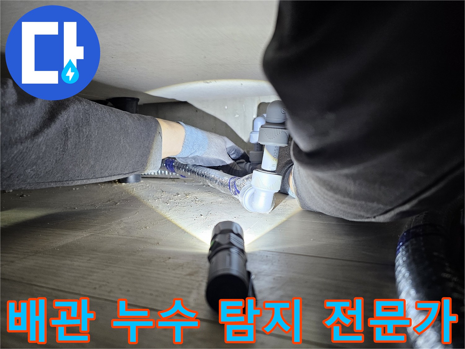 누수-탐지-전문가가-어두운-공간에서-배관-연결부를-확인하는-모습