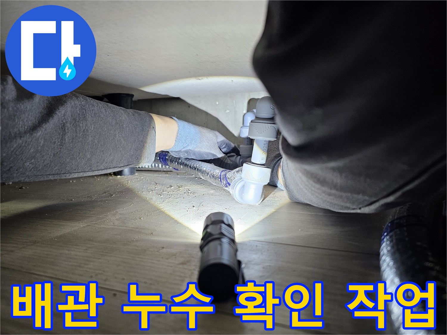 숙련된-기술자가-좁은-공간에서-손전등을-사용하여-배관-누수-여부를-확인하는-장면