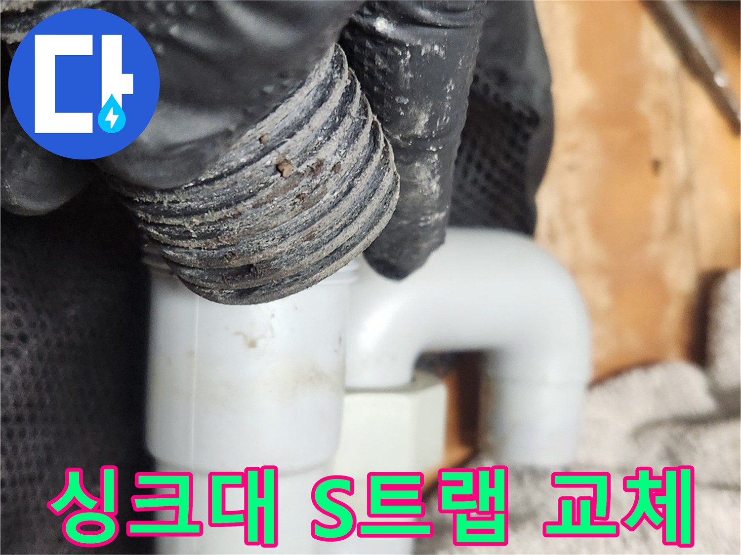 작업자가 검은 장갑을 끼고-오래되어 손상된 S트랩 배관을-새로운 부품으로 교체하기 위해 분리하고 있습니다