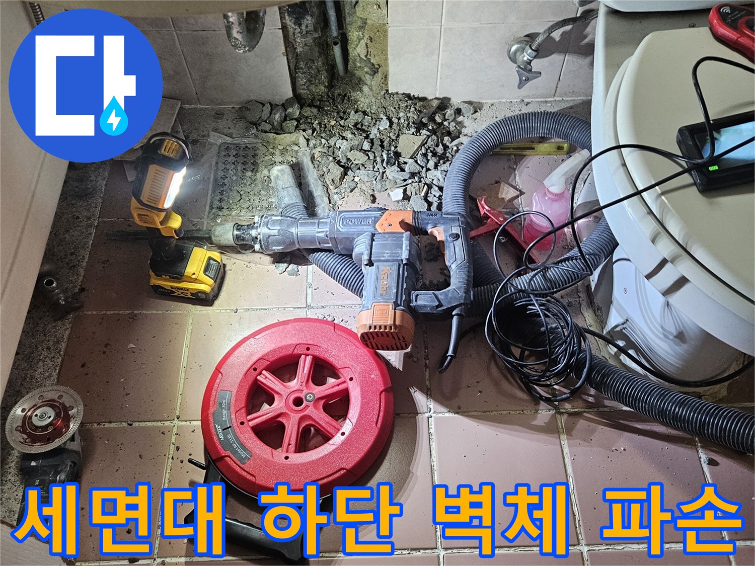세면대 아래쪽 타일을 깨서 매립된 배관을 드러낸 공사 장면입니다.