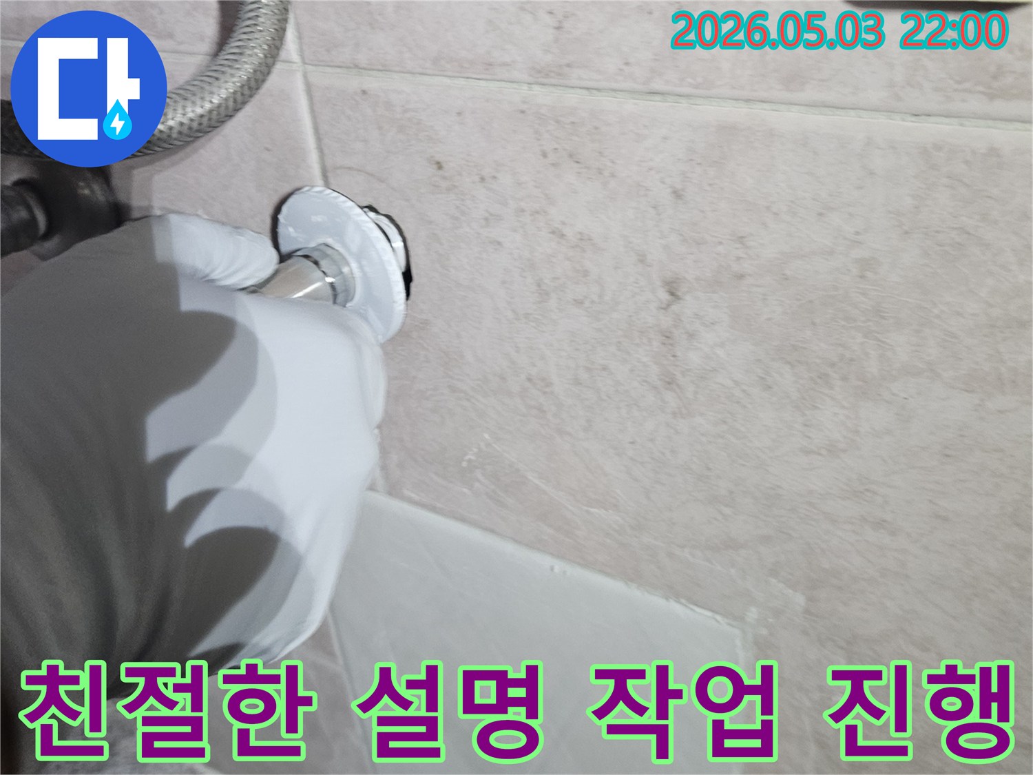 전문 엔지니어가 흰 장갑을 끼고-벽면의 수도 배관 연결 부위를-점검하며 고객에게-친절하게 설명하는 모습