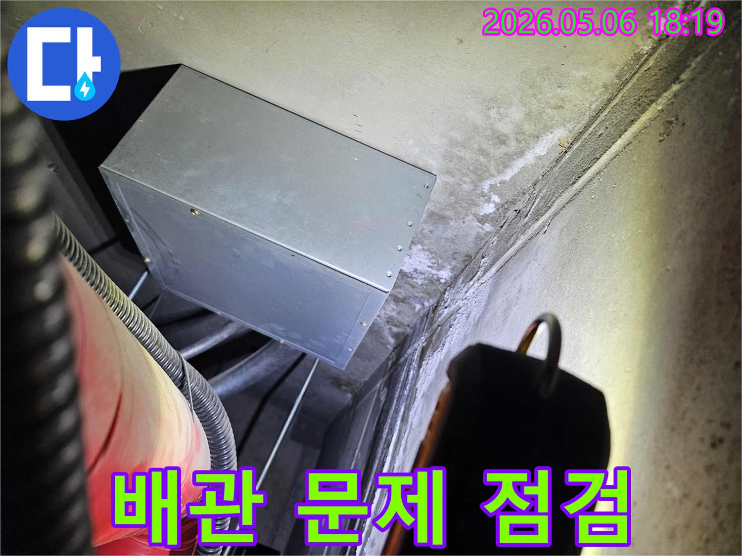 어두운 공간에서-배관 주변의-누수 흔적을-손전등으로 비춰-집중 점검하는-전문가의 모습입니다.