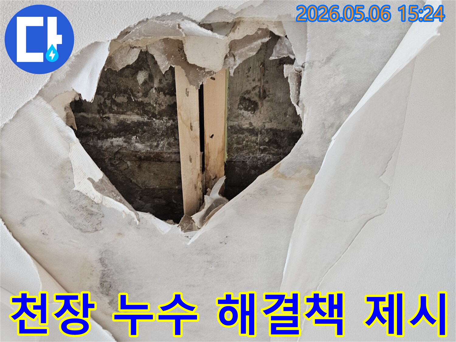 천장 벽지가 젖고-뜯겨져 내부 구조물이 노출된 누수 현장에서 전문가의 해결책이 필요한 모습입니다.