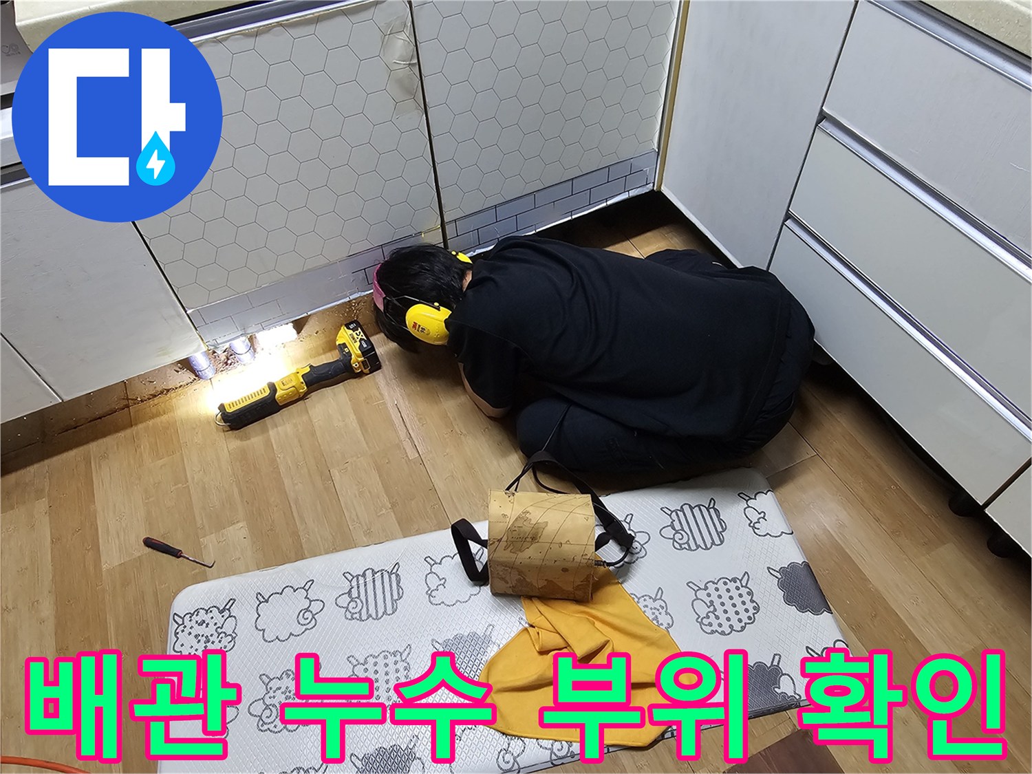 싱크대 하단 어두운 배관 주변을 점검하는 작업자의 모습