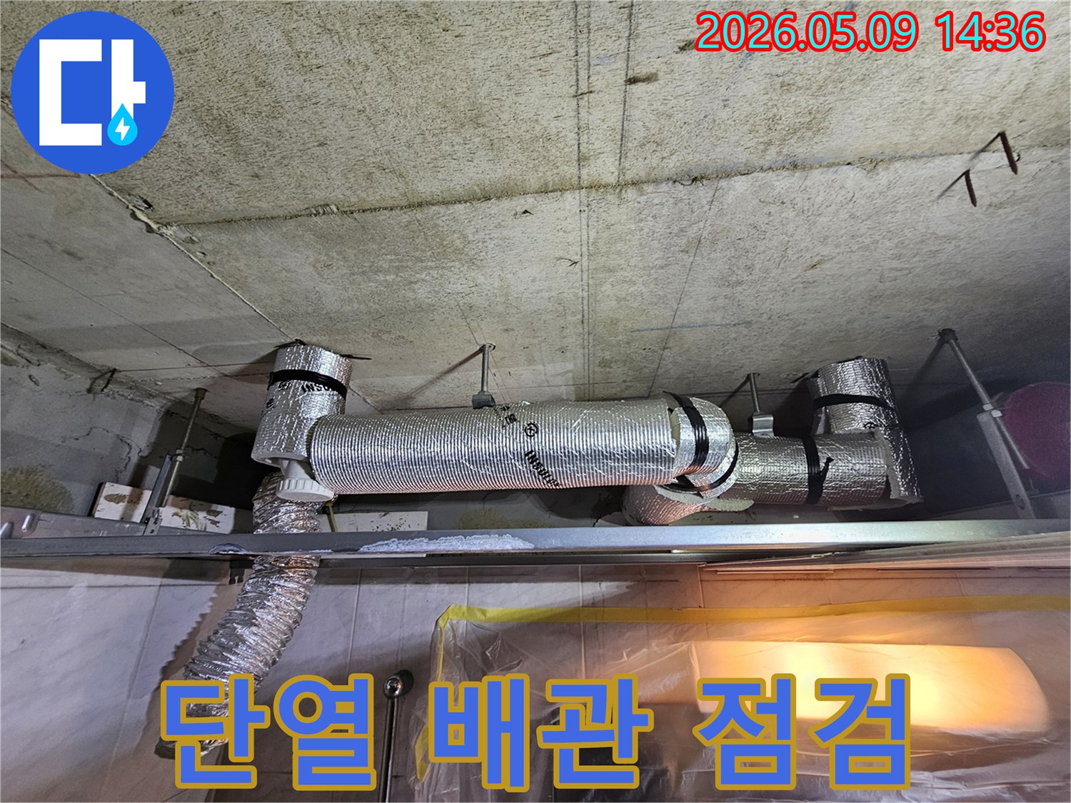 주방 천장 배관의 현재 상태를 점검하는 모습으로-단열재로 감싸인 배관과 주변 콘크리트의 습기 여부를 확인하고 있습니다.