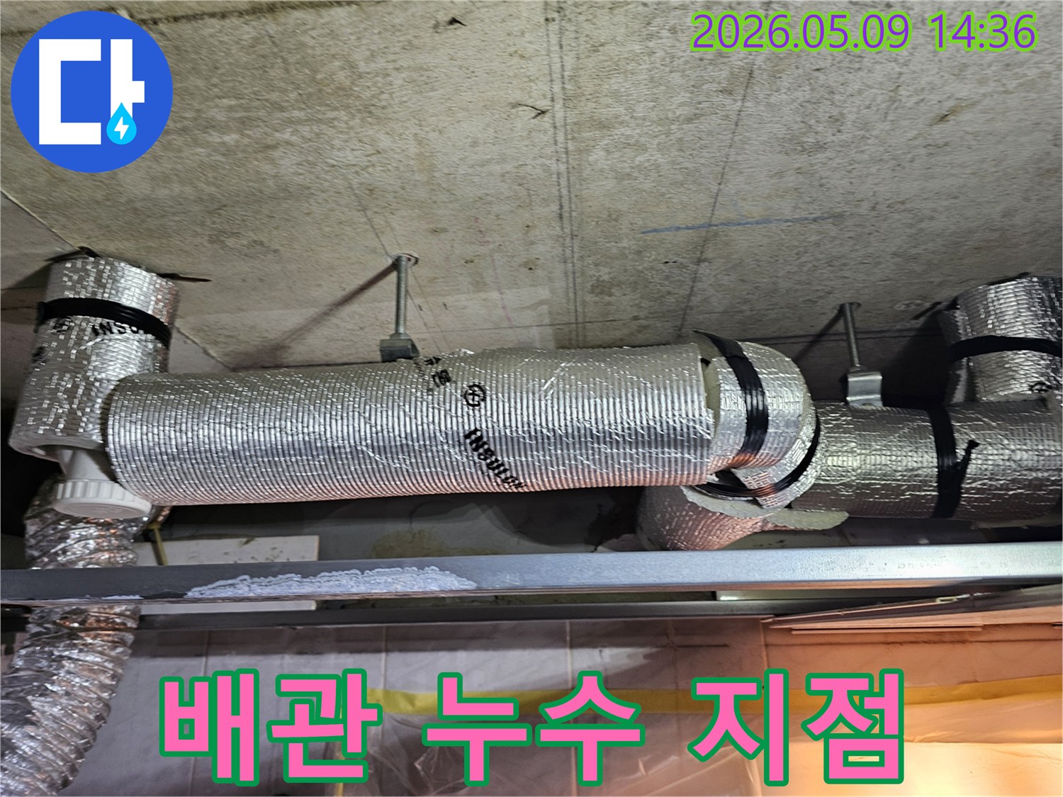 천장 콘크리트 구조물에 고정된 단열 배관 아래 금속 선반에 하얗게 굳은 물 자국