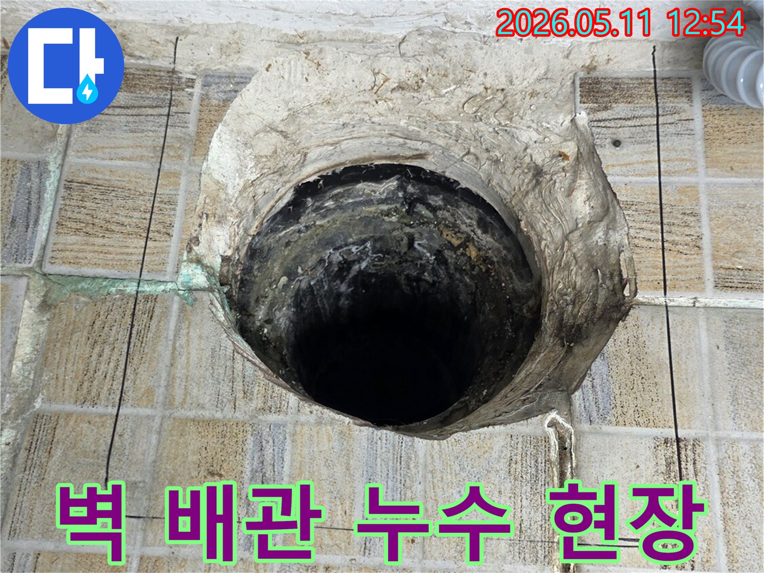 이 이미지는-서울 양천구 아파트에서-발견된-벽면 배관 누수-현장을 보여줍니다-오래된 타일과-손상된 배관 구멍이-명확하게 드러나 있습니다