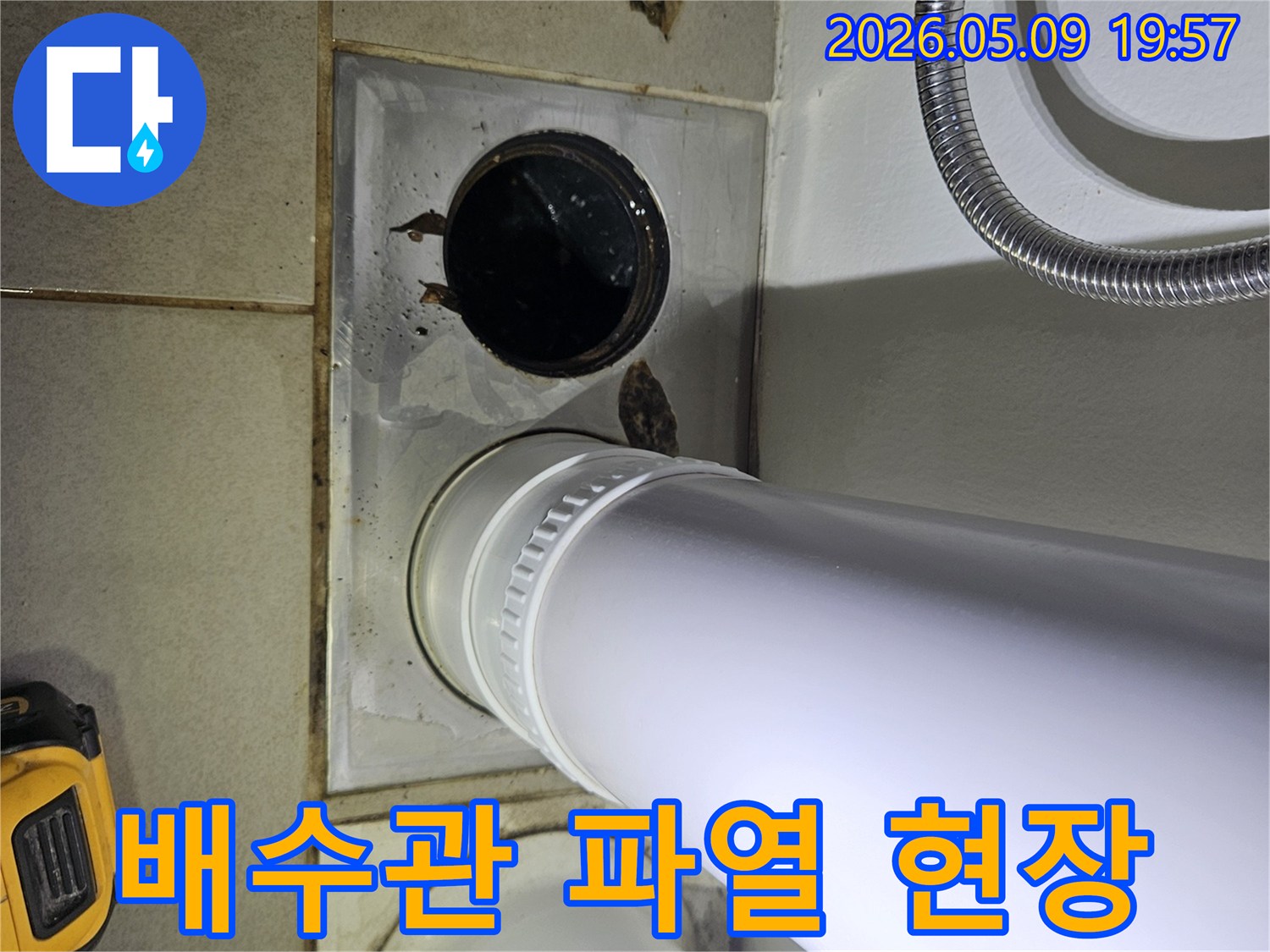 이 사진은 욕실 바닥의 배수관 주변에서 발생한 물 고임과 오염 현장을 보여주며-배관 파열 가능성을 시사합니다.