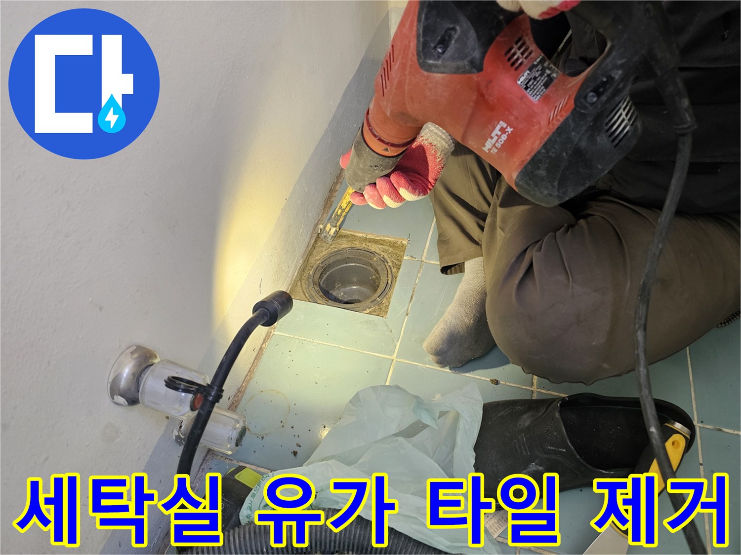 함마드릴을 사용하여 세탁실 배수구 주변 타일을 걷어내는 장면