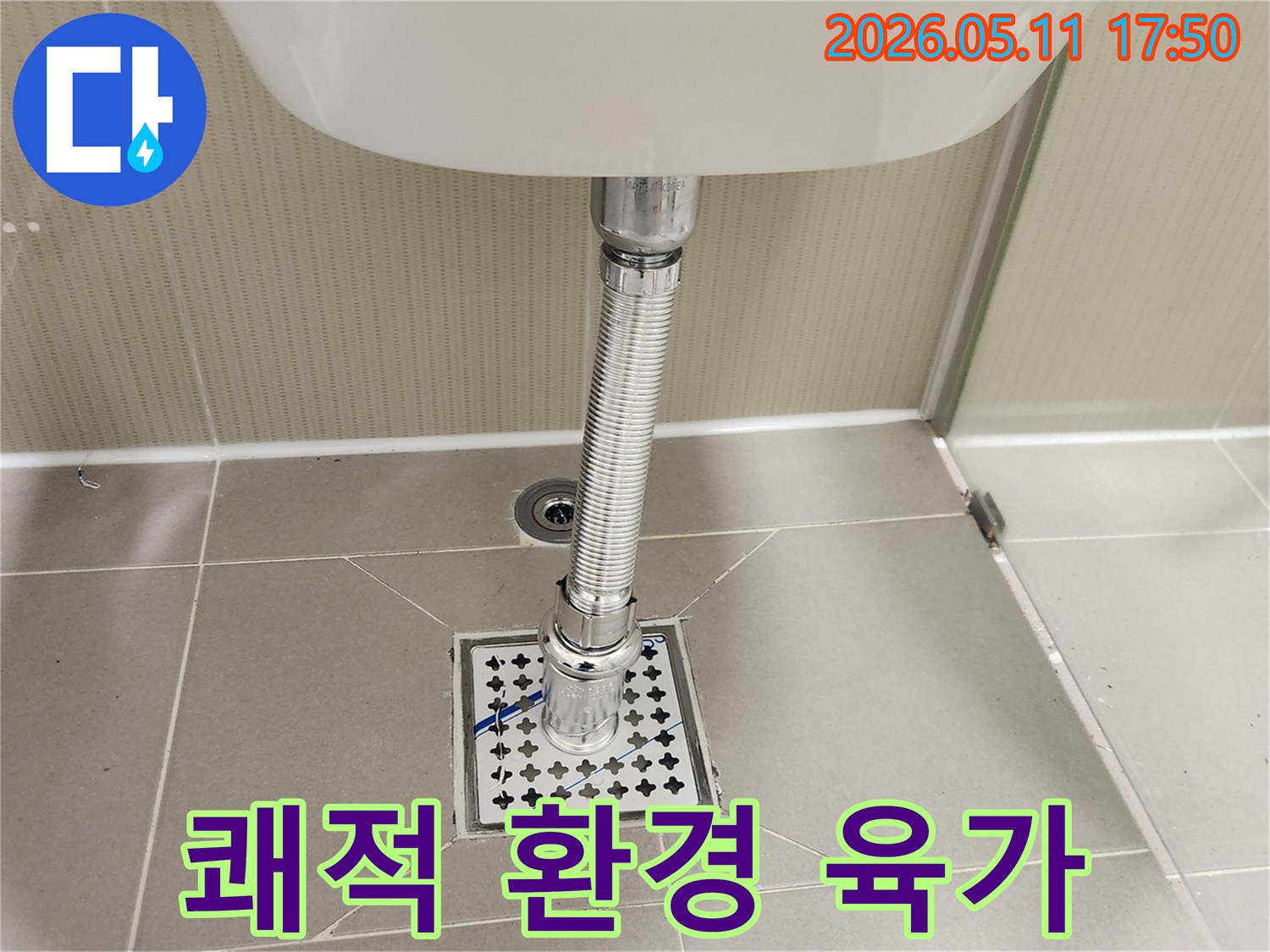 새롭게 설치된-욕실 바닥의-육가 배수망과-세면대 배수관이-깔끔하게-연결되어-쾌적한 욕실 환경을-조성한-모습입니다.