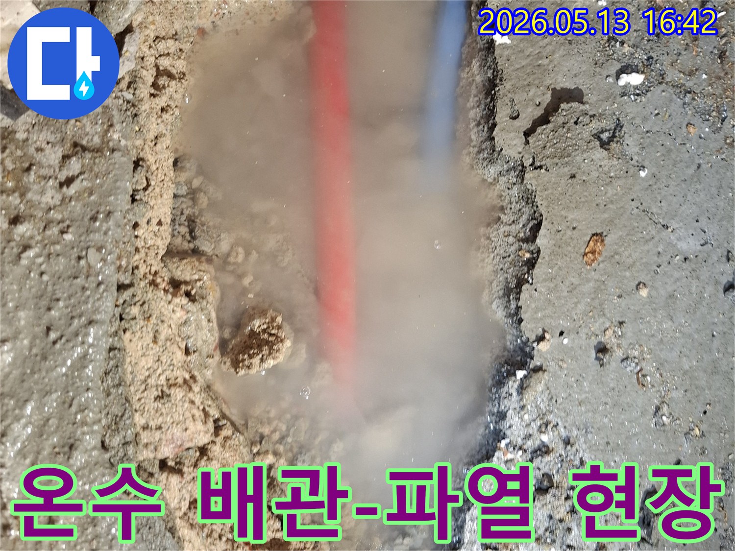 파헤쳐진 콘크리트 바닥 아래-붉은색과 푸른색 배관이 보이고-흙탕물과 함께-수증기가 솟아오르는-심각한 누수 상황을 담은 이미지