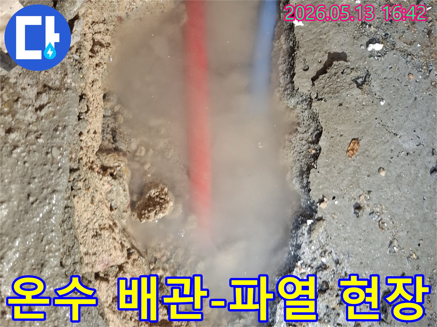 파헤쳐진 콘크리트 바닥 아래-붉은색과 푸른색 배관이 보이고-흙탕물과 함께-수증기가 솟아오르는-심각한 누수 상황을 담은 이미지