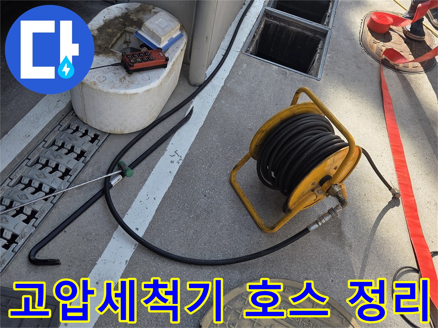맨홀 근처에 배치된 노란색 고압 세척 호스 릴과 장비