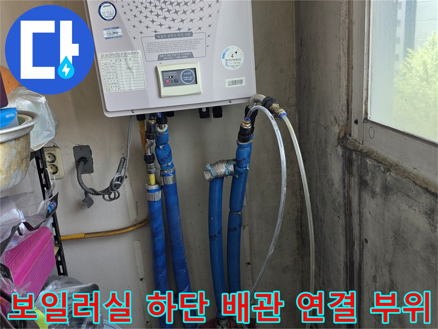 보일러 밑에 설치된 파란색 배관과 흰색 호스의 상세 모습