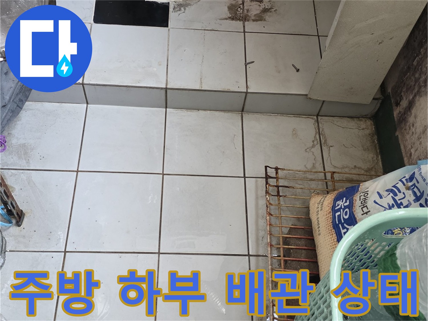 싱크대 아래 파란색 관과 타일 벽면의 근접 촬영본
