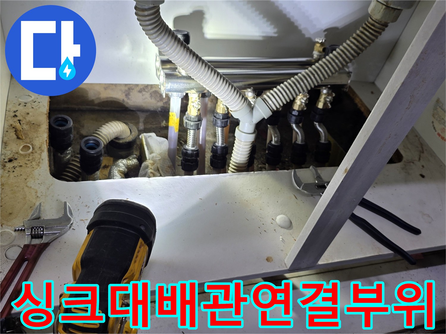 싱크대 하단 분배기와 주름관의 복잡한 연결 구조를 보여주는 사진입니다.