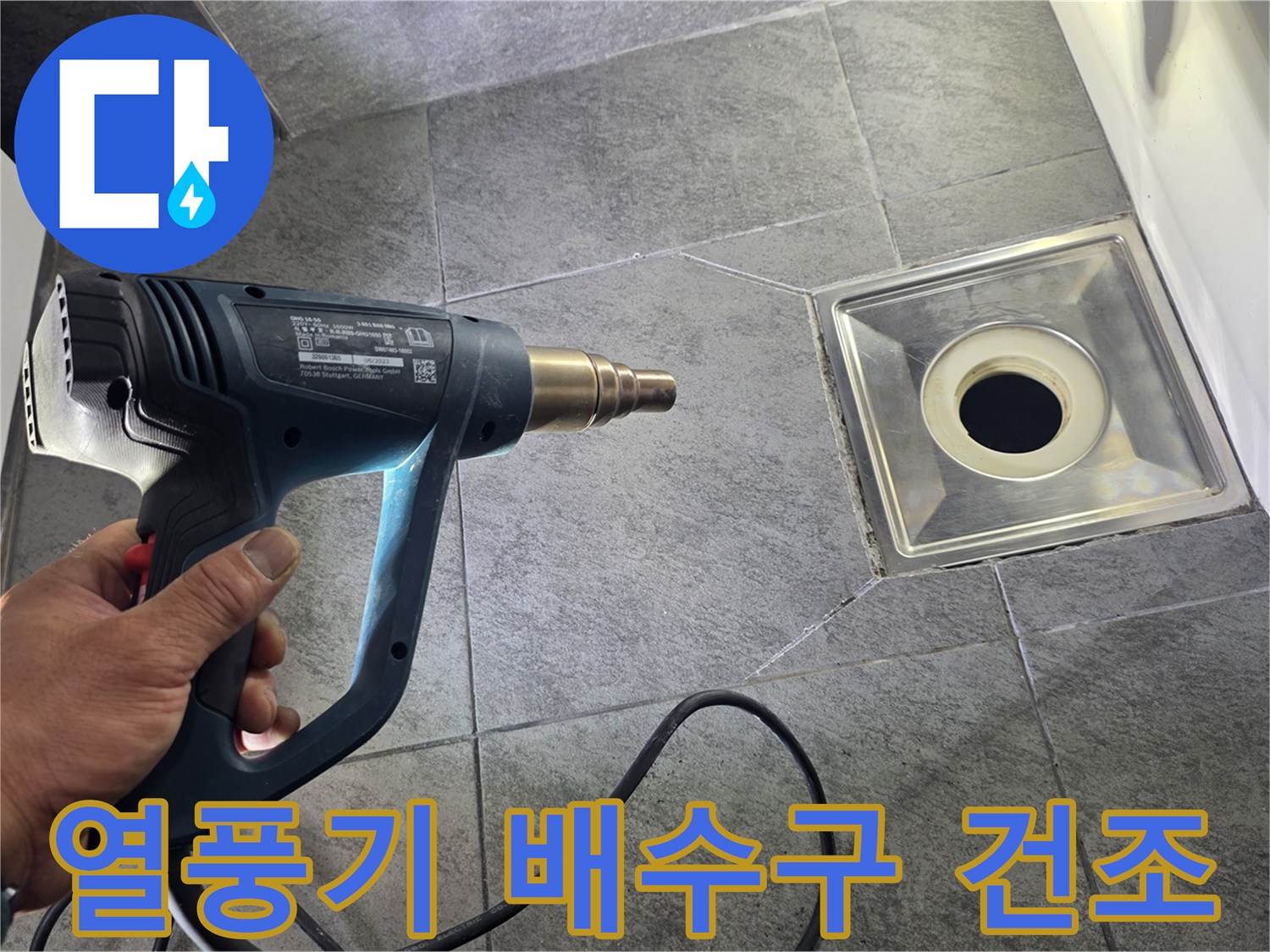 배수구 주변 습기를 제거하기 위해 열풍기로 건조하는 모습