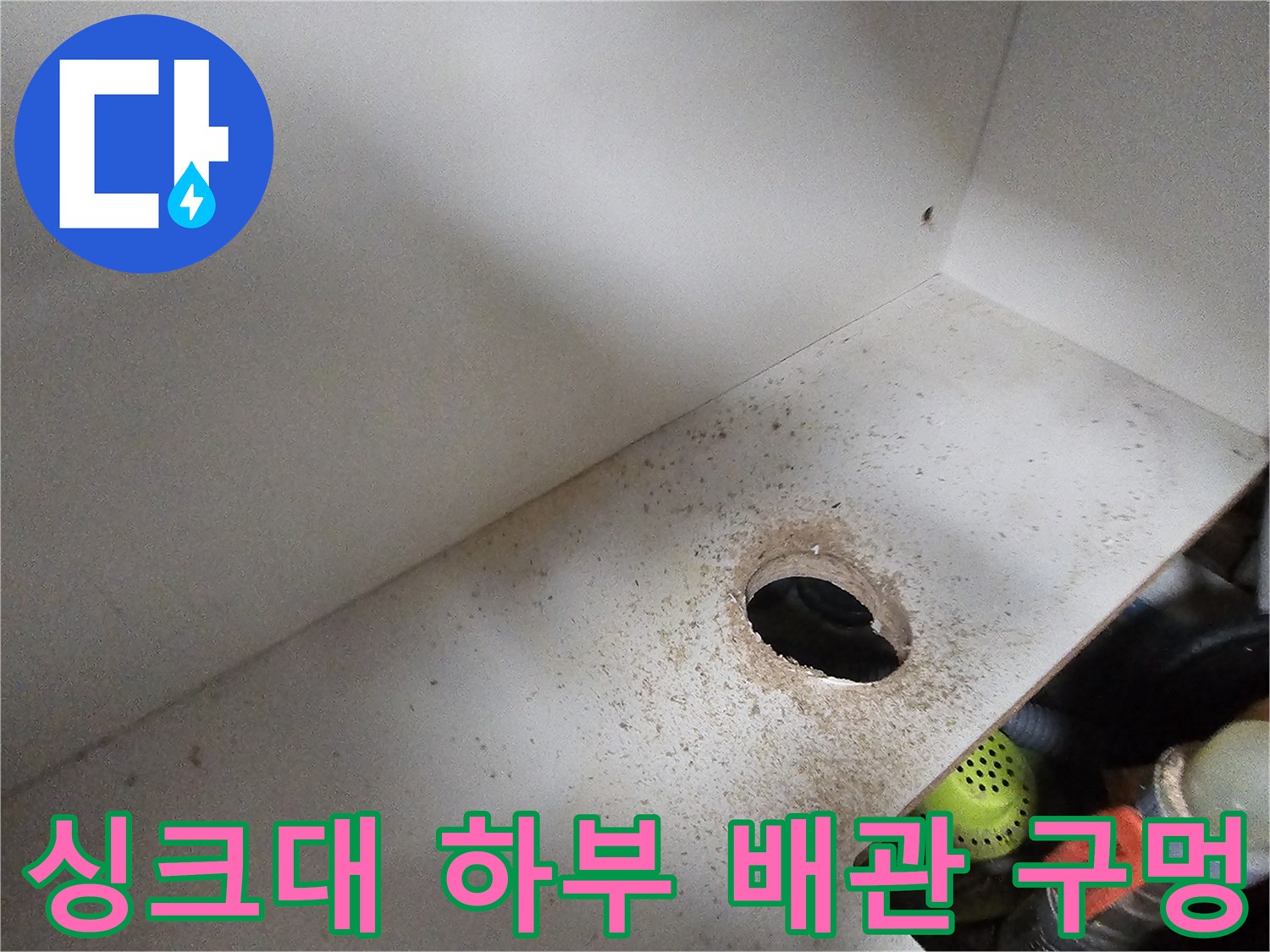 주방 싱크대 하부장 내부의 배관 관통 부위와 주변 오염 상태를 나타내는 사진