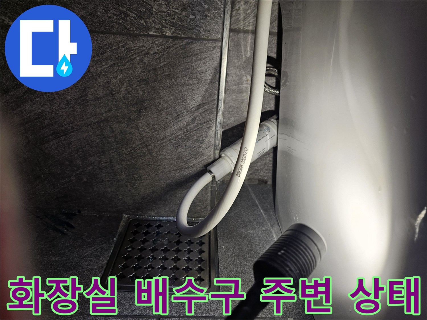타일 바닥의 배수구와 변기 급수 호스가 연결된 부위 촬영