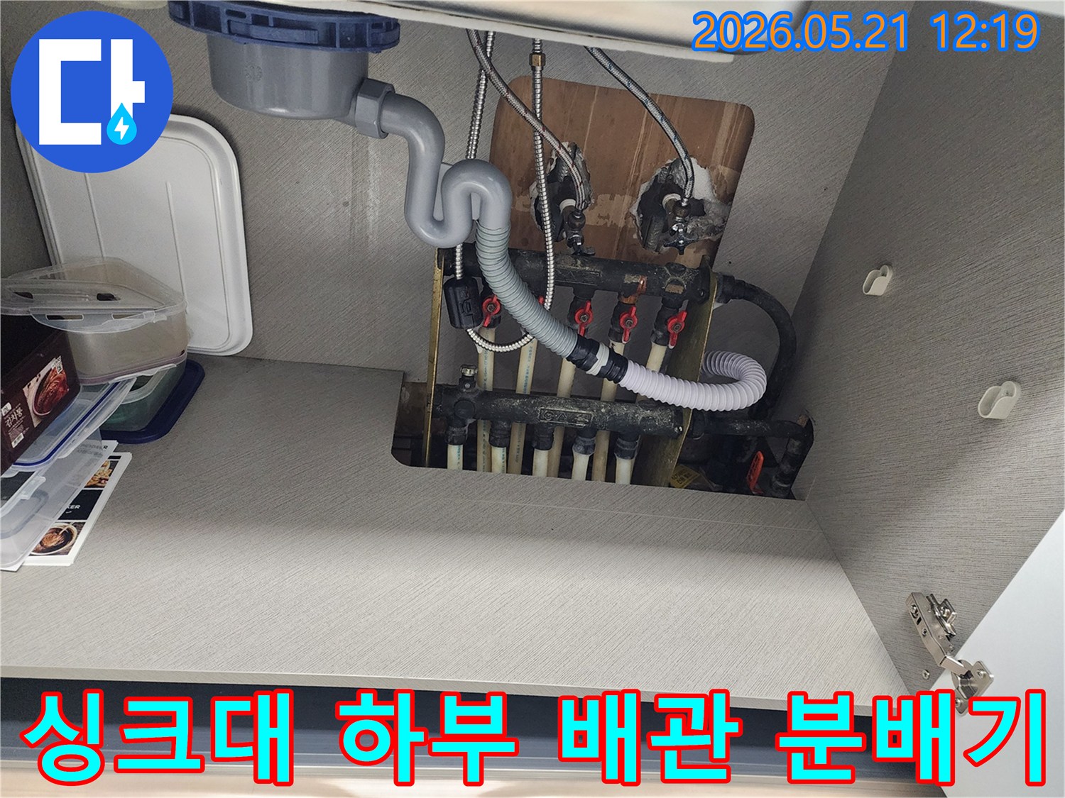 싱크대 하부에서 발견된 배관과 분배기-누수 점검을 위해 촬영된 이미지입니다.