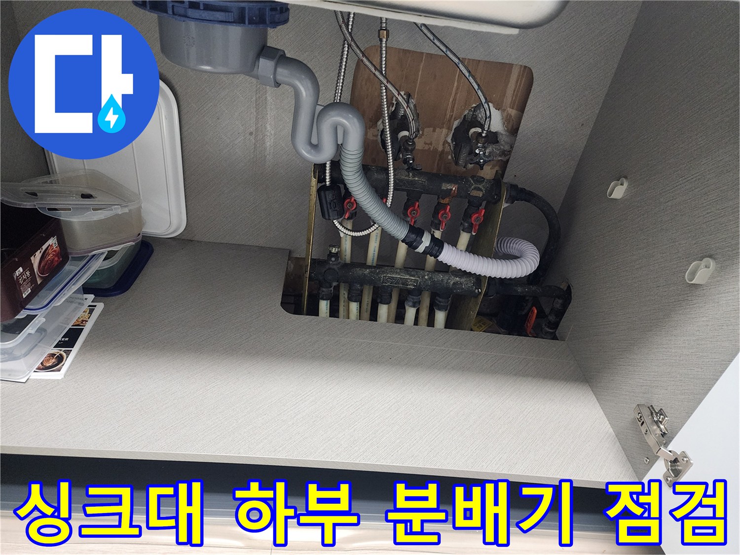 싱크대 하부장 내부-분배기와 흰색 배관의 연결 상태를 보여주는 사진