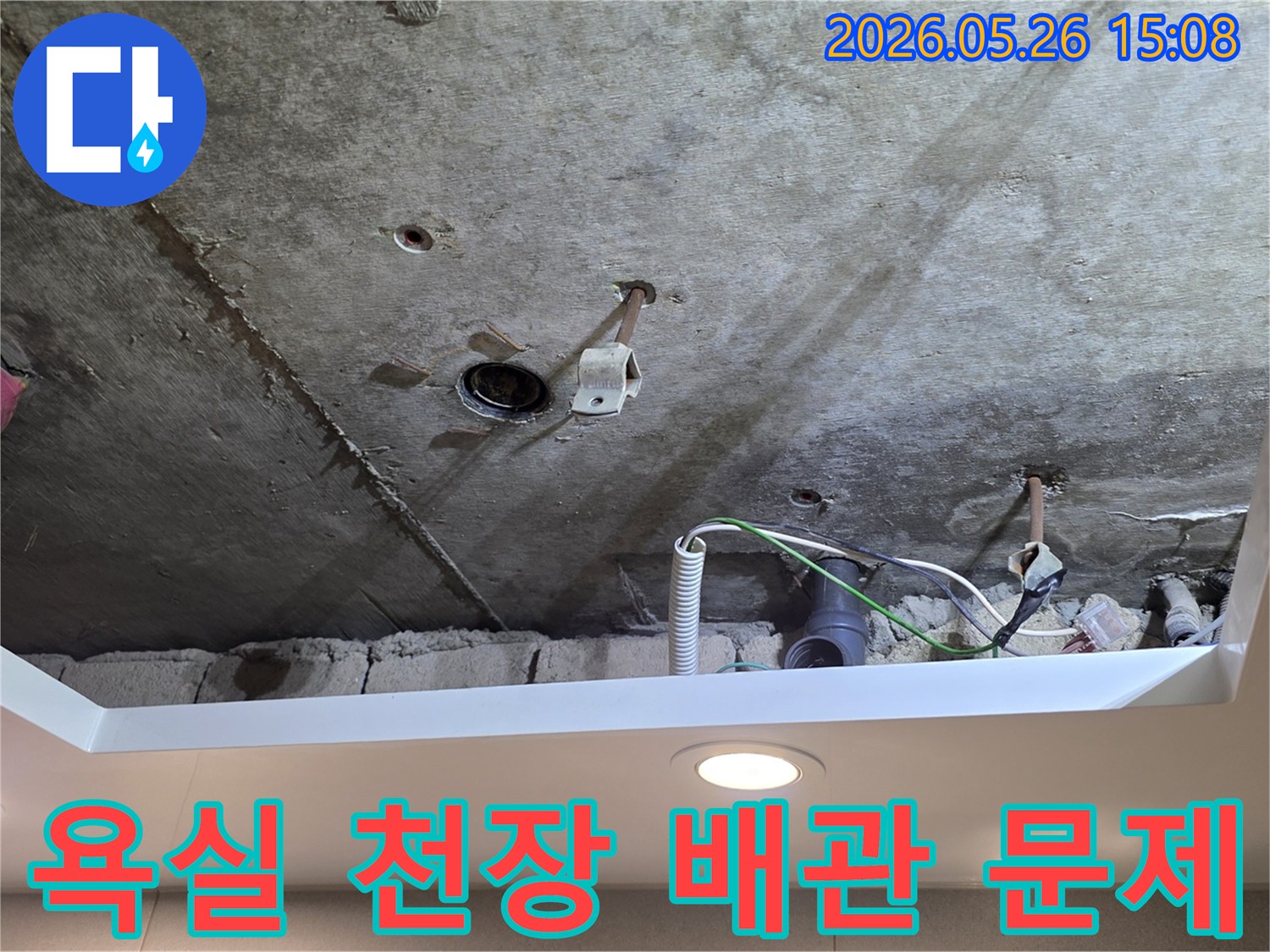 욕실 천장 아래-노출된 배관에서-누수가-발생하여-점검 중인-장면입니다