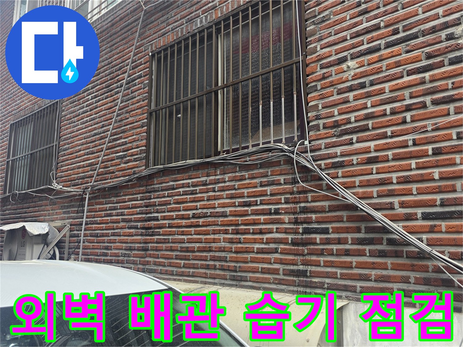 창문 아래 벽돌 외벽과 연결된 외부 배관의 모습