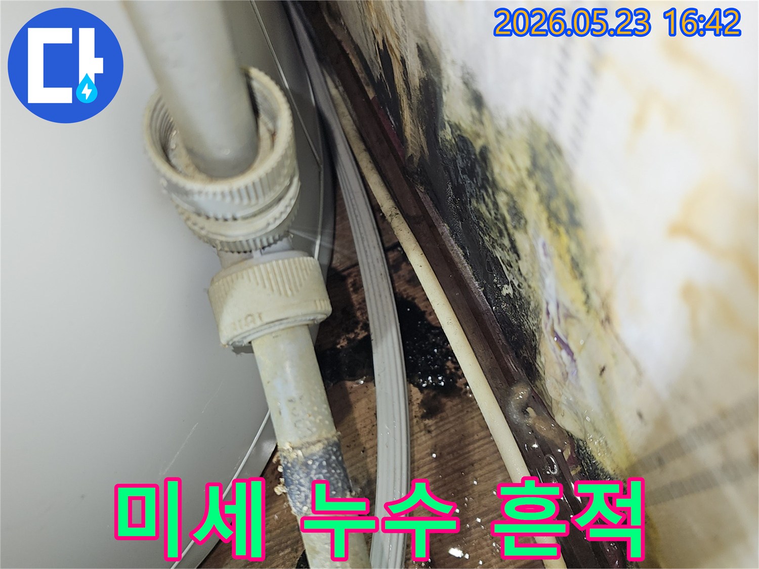 배관 연결부에서 발생한-미세한 누수로 인한 물자국과-오염 흔적을 보여주는 사진입니다.